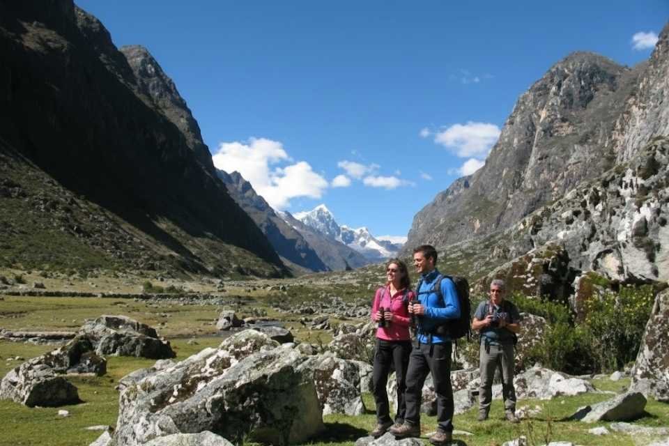Trekking group gazing at the pyramidal face of Alpamayo from the Cedros ravine base camp with Andeando Peru certified guides.